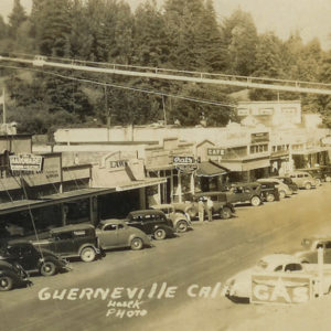 Old Cars Parked in Front of Stores, Shops, Cafes and Bars Along Main Street in Guerneville with moutains and Redwood Trees in the Background, Circa 1920